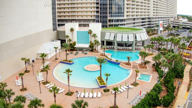 Un hotel con varias piscinas, palmeras y zonas de descanso.