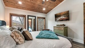 A bedroom with a large bed, wooden ceiling, and a painting on the wall. - Fall Getaway! Hot Tub! Mountain Views! (Gatlinburg)