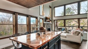 A spacious kitchen with a large island, wooden ceiling, and large windows offering views of the outdoors. - Fall Getaway! Hot Tub! Mountain Views! (Gatlinburg)