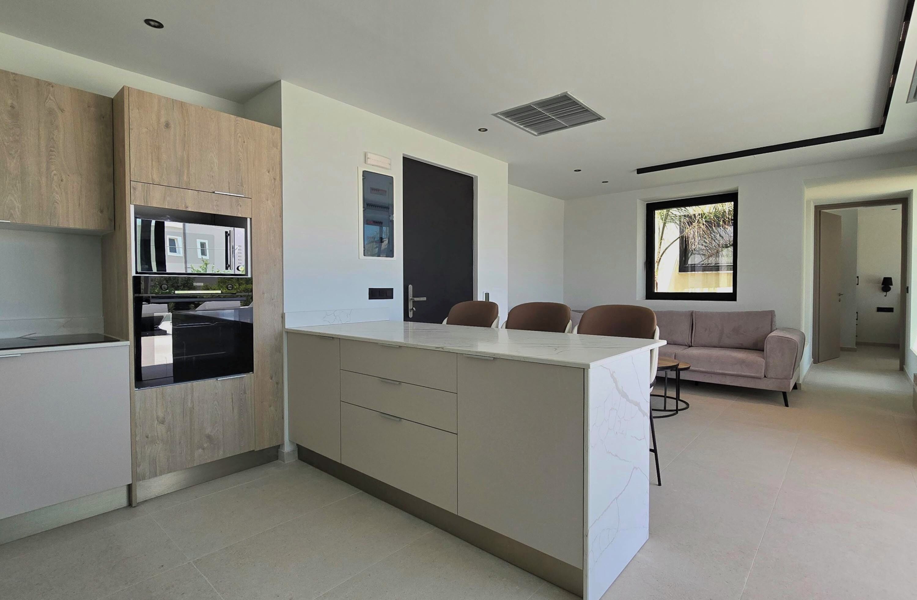 Una cucina moderna con mobili in legno, piano cottura integrato e zona pranzo con divano e sedie.
