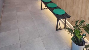 A hallway with a wooden wall, a bench with green seats, and a potted plant. - GLOBAL Apartments & Rooms (L'Hospitalet de Llobregat)