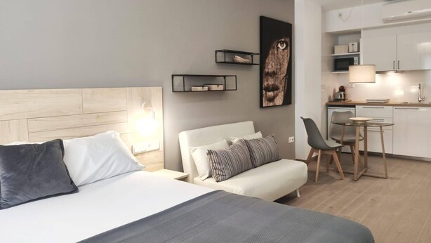 A modern hotel room with a bed, bedside table, and a small kitchenette. - GLOBAL Apartments & Rooms (L'Hospitalet de Llobregat)