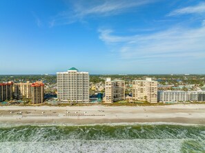 A coastal cityscape with high-rise buildings, a beach, and ocean waves.