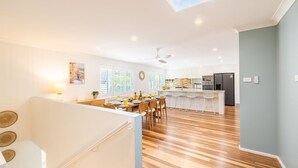 A modern kitchen with white cabinets, a central island, and a dining area with wooden chairs.