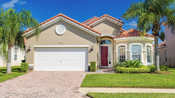 A two-story house with a red door, a garage, and a well-maintained lawn. - The Hideaway@Tuscan Hills, a modern 4 bedroom, 3 bath luxury home (Davenport)