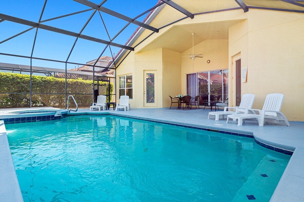 Une piscine à l’eau d’un bleu cristallin, entourée de chaises longues blanches et d’un patio couvert.