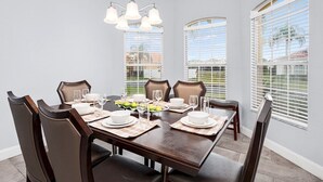 A dining room with a rectangular table set for six, surrounded by six chairs. - The Hideaway@Tuscan Hills, a modern 4 bedroom, 3 bath luxury home (Davenport)