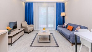 Una sala de estar moderna con un sofá, un sillón, una mesa de centro, televisor y una lámpara.
