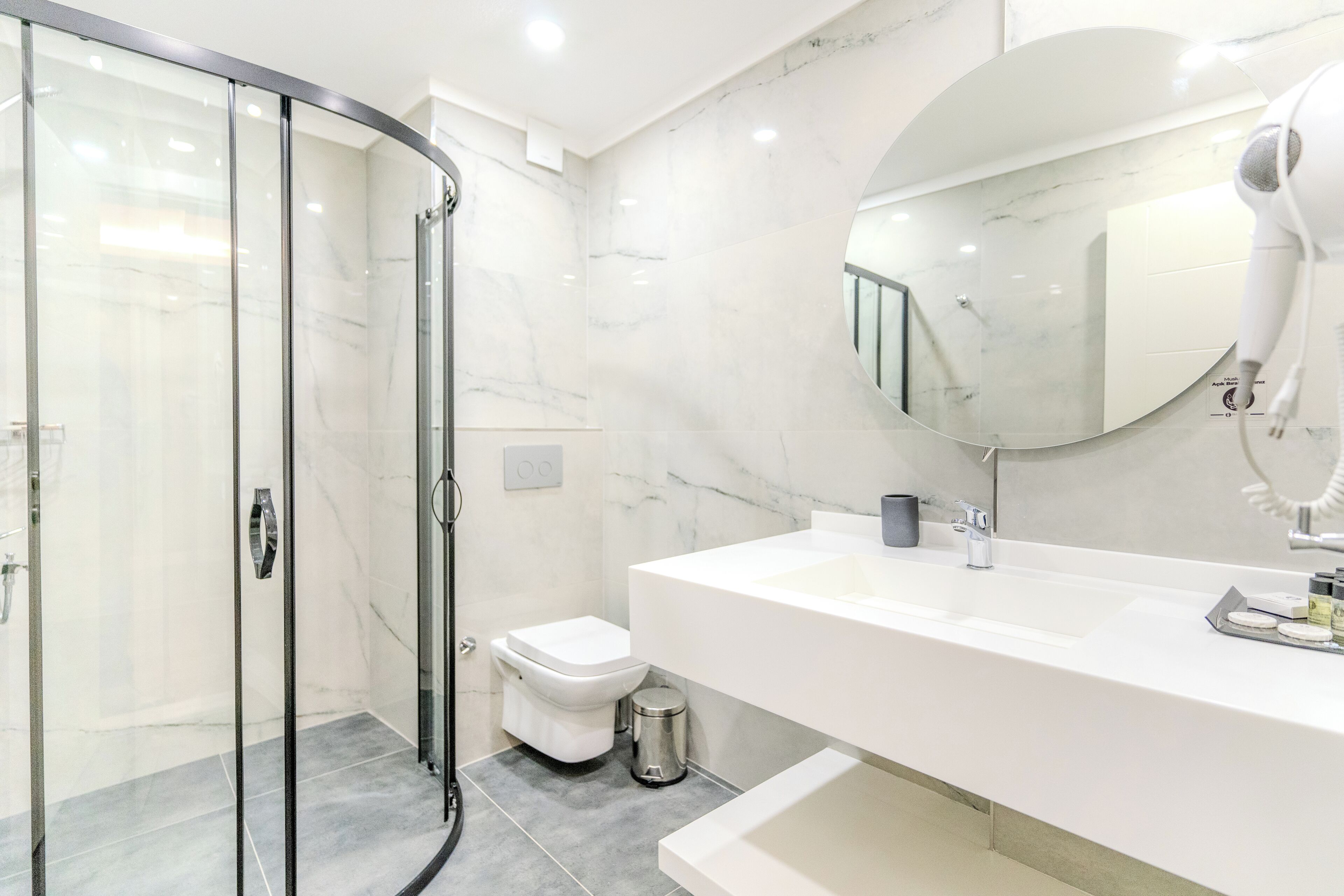 Un baño moderno con cabina de ducha de vidrio, un lavamanos blanco y un espejo grande.