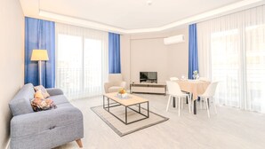 Una sala de estar moderna con un sofá gris, una mesa de centro y un comedor con sillas blancas y una mesa.