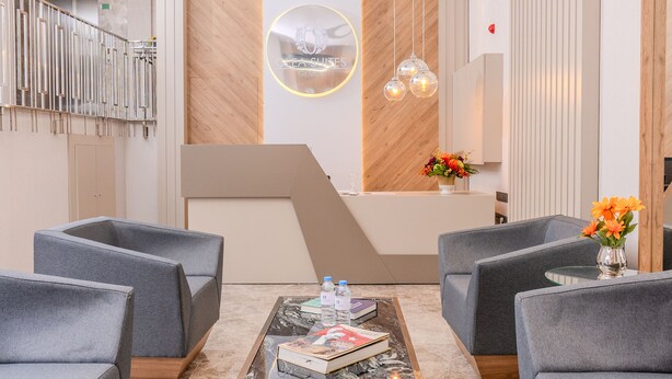 Un vestíbulo moderno con sofás grises, una mesa de centro y un mostrador de recepción.