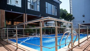 A swimming pool with a metal safety railing and a wooden deck. - Nevada Hotels and Suites Lekki (Lekki)