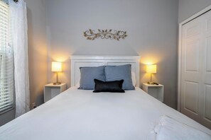 A neatly made bed with two pillows, a decorative wall piece, and bedside lamps.