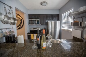 A kitchen with stainless steel appliances, a granite countertop, and hanging pots.