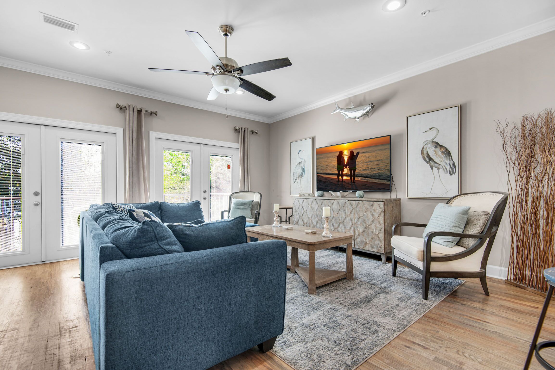 A living room with a blue sofa, a wooden coffee table, a chair, and a ceiling fan.