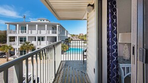 Un balcon donnant sur une piscine et un immeuble de deux étages en arrière-plan.