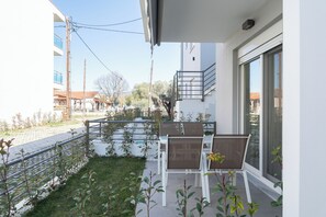 A balcony with outdoor seating, a view of the street, and a building in the background.