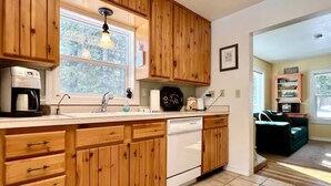 A kitchen with wooden cabinets, a dishwasher, and a window above the sink. - Wonderful West Glacier Basecamp Property (Columbia Falls)