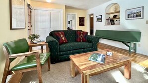 A cozy living room with a green sofa, a wooden coffee table, and a green bench. - Wonderful West Glacier Basecamp Property (Columbia Falls)
