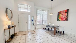 Amplia sala de estar con una mesa de comedor, un espejo grande y una lámpara colgante moderna.
