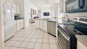 Una cocina moderna con armarios blancos, un microondas negro y un lavavajillas integrado.