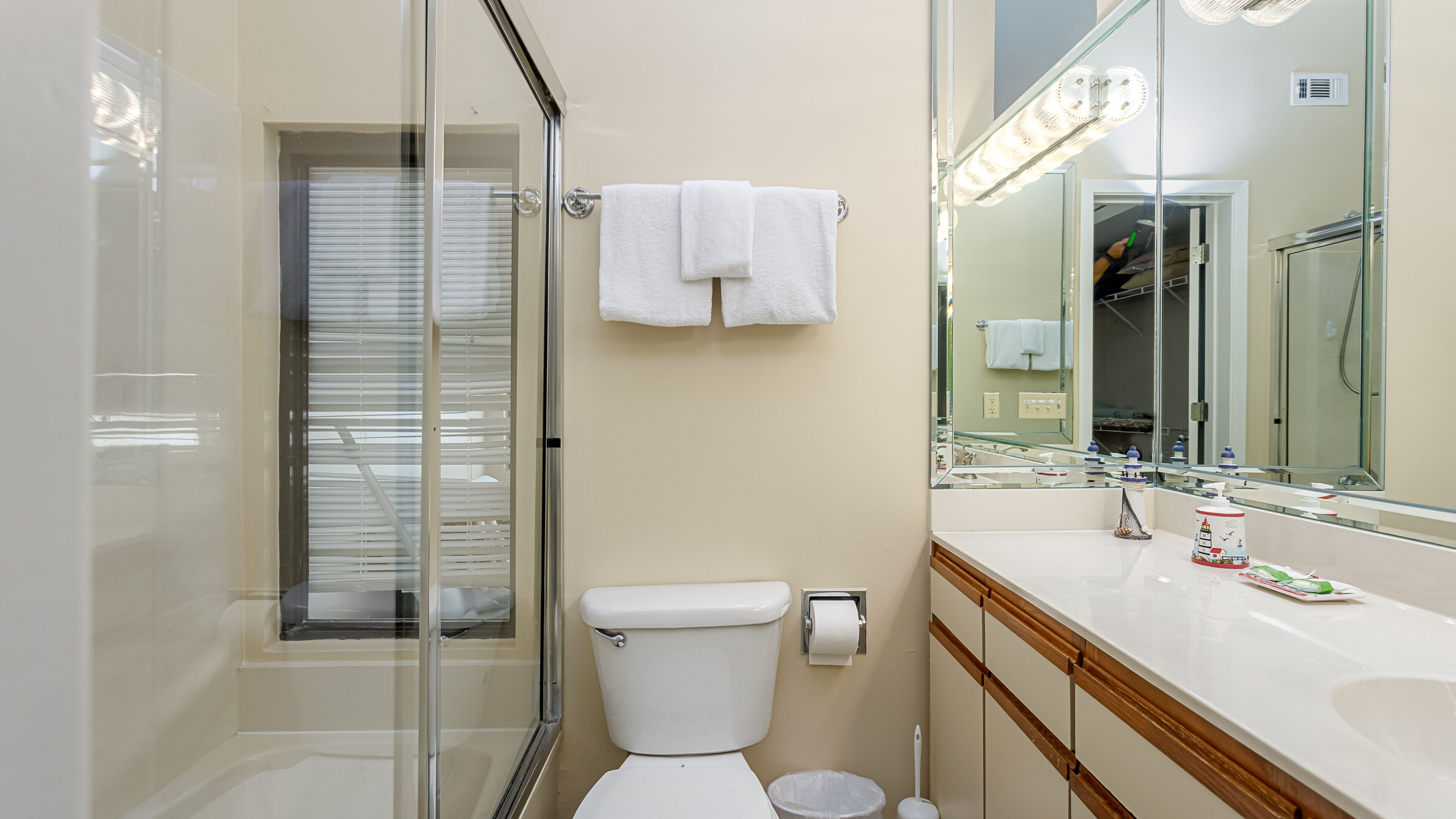 A modern bathroom with a glass-enclosed shower, a toilet, a sink with a mirror, and a towel hanging on a rack.
