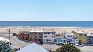 Une rue côtière bordée d’immeubles, avec une plage et l’océan.