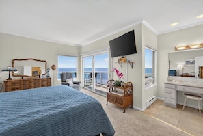 Une chambre dotée d’un grand lit, d’un bureau, d’une chaise, d’une télévision et d’un balcon avec vue.