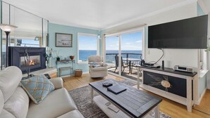 Un salon avec une cheminée, un canapé, une table basse et une vue sur la mer.