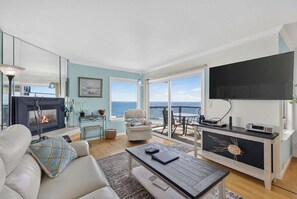 Un salon avec une cheminée, un canapé, une table basse et une vue sur la mer.