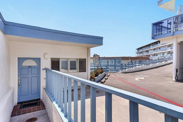 A residential building with a blue door, a small porch with a railing, and a staircase leading to the entrance. - Overlooking the Ocean! (Aptos)