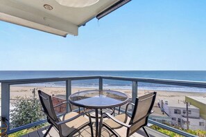 A balcony with a glass table and chairs overlooking a beach. - Overlooking the Ocean! (Aptos)