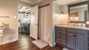 A modern kitchen with dark cabinets, a marble countertop, and a large mirror. - The 1840's Goat House (Elburn)