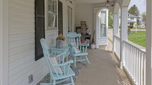 A porch with two rocking chairs, a small table with a vase, and a sign that reads "The Garden". - The 1840's Goat House (Elburn)