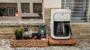 A kitchen with a coffee maker, a basket of coffee beans, and a decorative shelf with small items. - Single Level on TPC Champions Course | 2 Bedroom (Scottsdale)