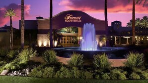 A hotel with a fountain in front, palm trees, and a sunset sky. - Single Level on TPC Champions Course | 2 Bedroom (Scottsdale)