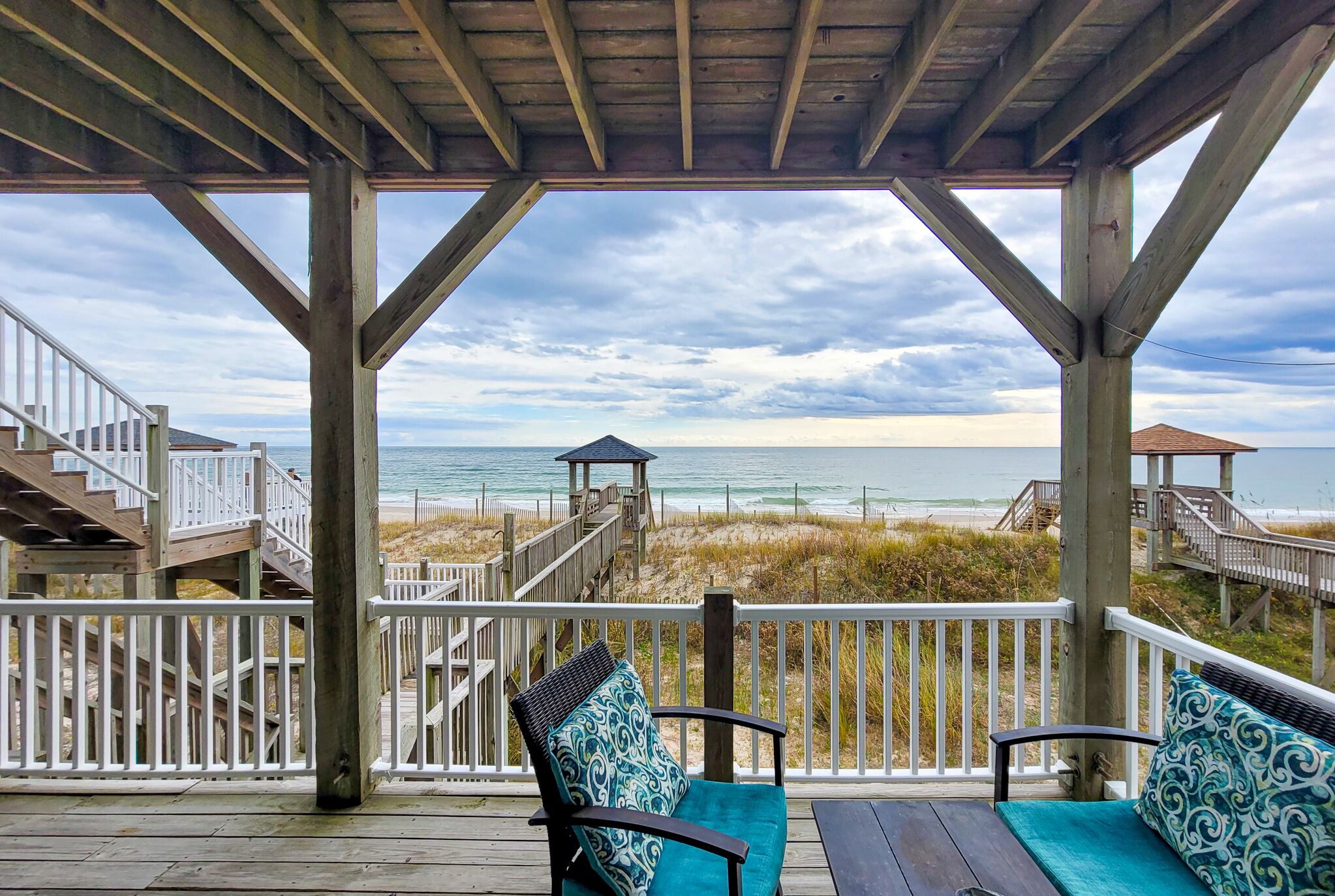 A wooden deck with a view of the beach and ocean.