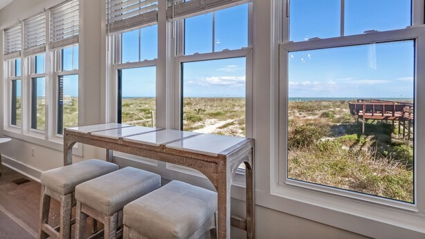 A room with large windows, a wooden table, and cushioned stools. - 2100 South Fletcher - Beautifully Updated, Oceanfront Bungalow (Fernandina Beach)