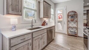 A modern kitchen with wooden cabinets, a sink, and a built-in oven. - 2100 South Fletcher - Beautifully Updated, Oceanfront Bungalow (Fernandina Beach)