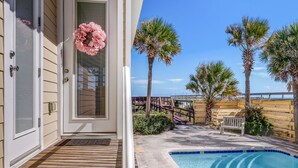 A pool area with a wooden deck, palm trees, and a bench. - 2100 South Fletcher - Beautifully Updated, Oceanfront Bungalow (Fernandina Beach)