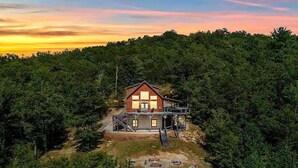A cabin with a wooden exterior, surrounded by dense forest, and a small deck area. - One-of-kind Views! Stunning Sunsets! Highly Sought after Location! (Marion)