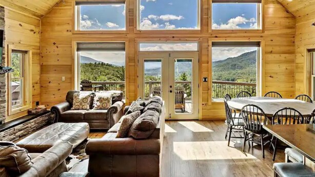 A wooden cabin with a high ceiling, large windows, a sofa, a dining table, and chairs. - One-of-kind Views! Stunning Sunsets! Highly Sought after Location! (Marion)
