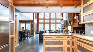 A modern kitchen with wooden cabinets, a central island, and large windows. - Rapids Rustic Retreat (Wisconsin Rapids)