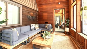 A wooden interior with a sofa, a coffee table, and a mirror reflecting a dining area. - Rapids Rustic Retreat (Wisconsin Rapids)