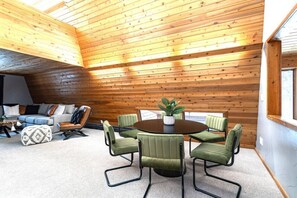 A room with a wooden ceiling, a round table with chairs, a sofa, and a lamp. - Rapids Rustic Retreat (Wisconsin Rapids)