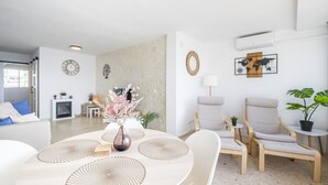Ein modernes Wohnzimmer mit einem runden Esstisch, zwei Sesseln, einer Couch und einem Kamin.