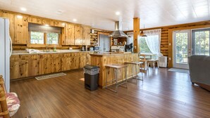 Un'ampia cucina con mobili in legno, un'isola centrale e un'area pranzo con tavolo e sedie.