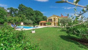 Ein Haus mit Swimmingpool, umgeben von üppigem Grün und Bäumen.