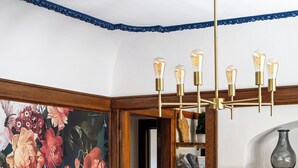 Comedor con una mesa de madera oscura, sillas negras y un mural floral.