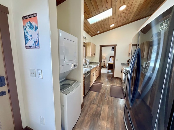 A kitchen with a stainless steel refrigerator, wooden cabinets, and a washing machine. - NEW! LAST MIN SPECIAL! Ski Chalet, Spacious, Clean, Close To Everything! (Big Sky)